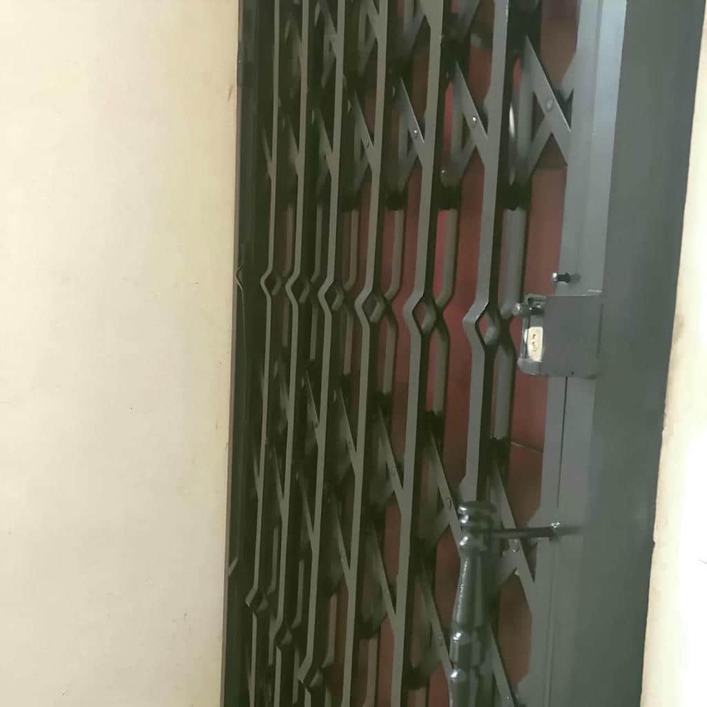 حفاظ درب آکاردئونی خاکستری پشت ورودی چوبی