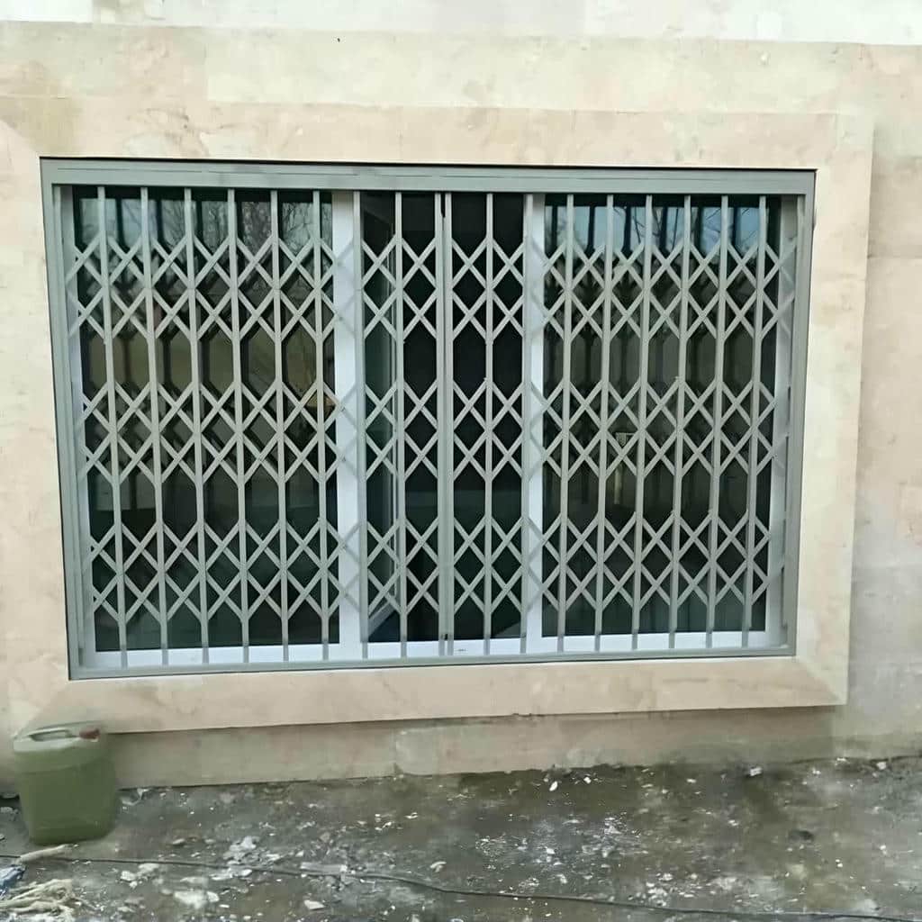 حفاظ درب آکاردئونی سفید کنار چهارچوب چوبی تبریز