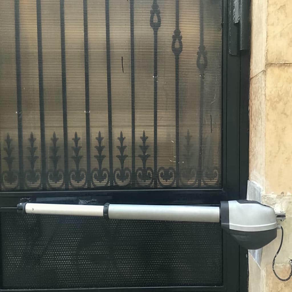 دربازکن بازویی مشکی روی دروازه فولادی آفتاب‌گیر