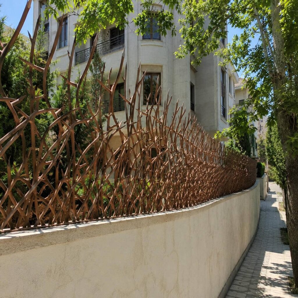 نرده سرنیزه ای خاکستری بر فراز دیوار ورودی مجتمع