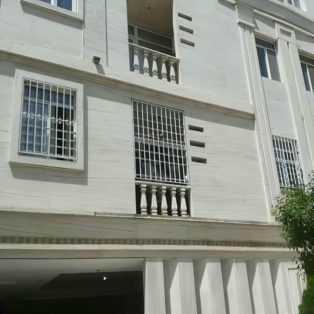 نرده سفید فلزی رو به حیاط مشترک مسکونی