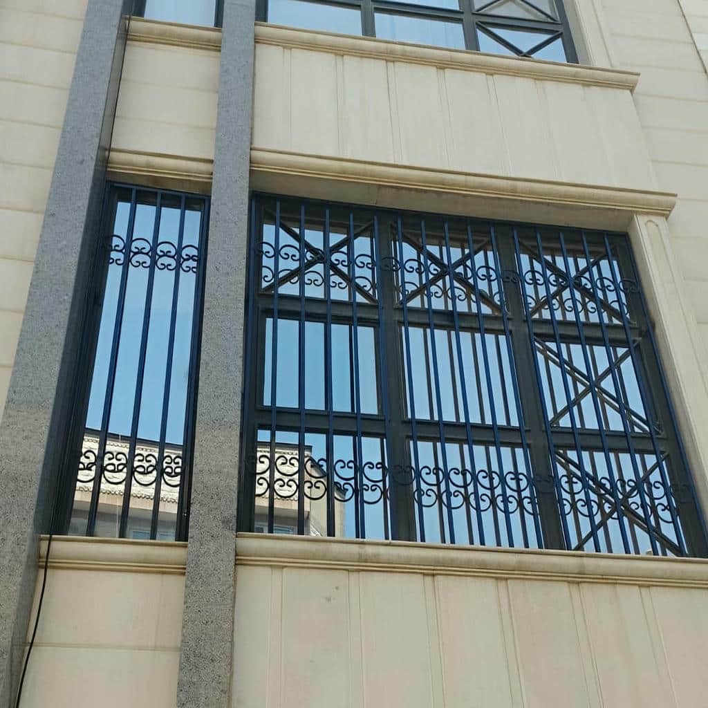 گارد پنجره ثابت با میله‌های عمودی روی نمای سنگی